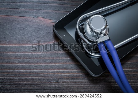 Medical stethoscope and digital tablet on vintage wooden board medicine concept