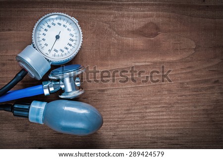 Medical stethoscope and blood pressure monitor on vintage wooden pine board medicine concept