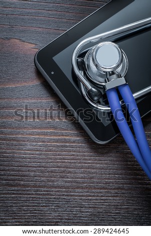 Medical stethoscope and touch-sensitive pad on vintage wooden background medicine concept