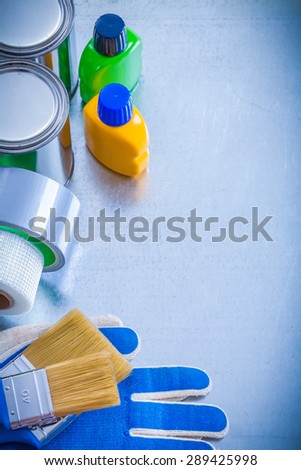 Paint cans bottles brushes household tapes and safety gloves on metallic background maintenance concept.