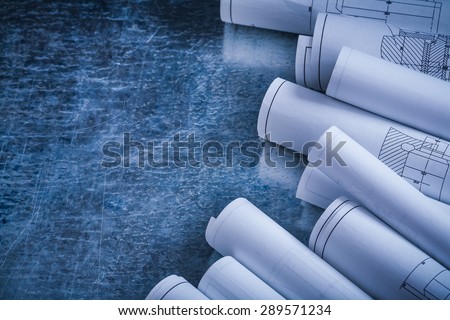 Metallic scratched background with heap of white blueprints horizontal version construction concept.