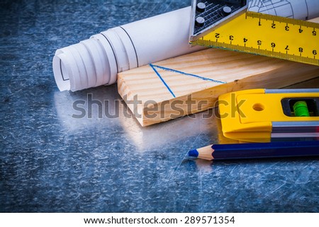 Pencil try square blueprints wooden stud and construction level on metallic scratched background maintenance concept.