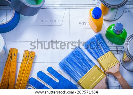 Wooden meter household tapes protective gloves and paint tools on blueprint construction concept.