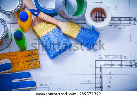 Wooden meter household tapes safety gloves and paint tools on blueprint maintenance concept.