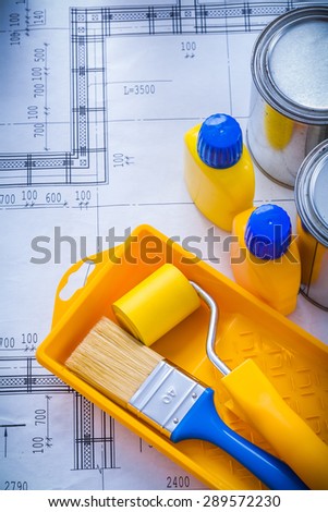 Blueprint with paint brush roller tray metal cans and plastic bottles construction concept.