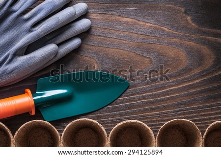 Vintage wooden board with rubber gloves peat pots and hand shovel gardening concept.