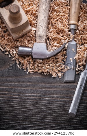 Vertical view of claw hammer chisels wooden shaving plane and planning chips on vintage wood board construction concept.