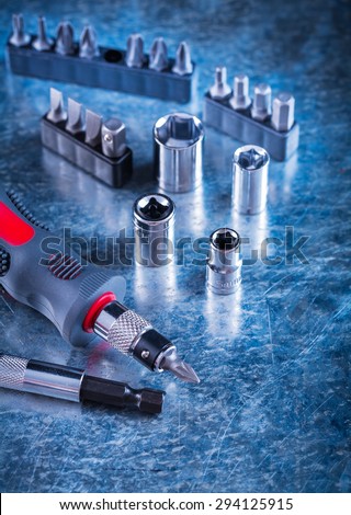 Toolset of insulated screwdriver with replaceable heads and bits on scratched metallic surface construction concept.