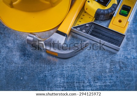 Try square construction level tape-measure hard hat and claw hammer on scratched metallic background maintenance concept.
