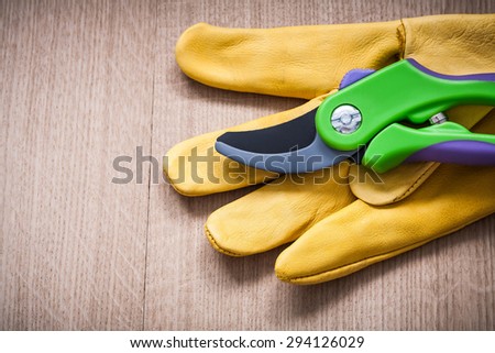 Agricultural leather safety glove with secateurs on wooden board gardening concept.
