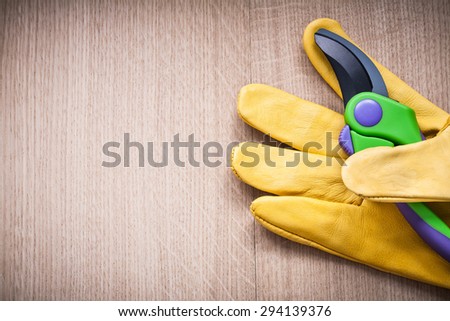 Yellow leather safety glove with secateurs on vintage board agricultural concept.