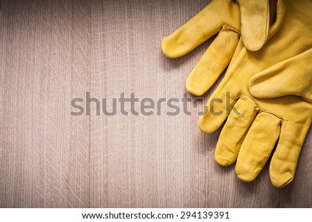 Pair of yellow leather safety gloves on wooden board copy space image gardening concept.