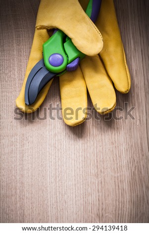 veritcal view yellow leather protective glove with garden pruner on wood board agricultural concept.