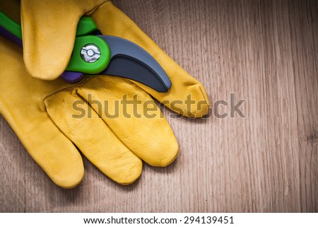Yellow leather protective glove with garden pruner on wood board agricultural concept.