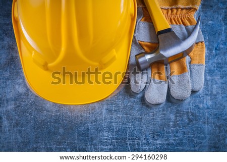 Safety gloves yellow building helmet and claw hammer on scratched metallic background maintenance concept.