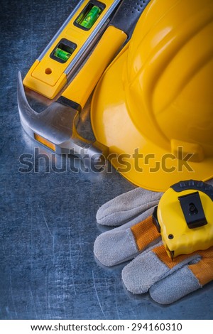 Safety working gloves hard hat construction level tape-line and metal claw hammer on scratched metallic background maintenance concept.