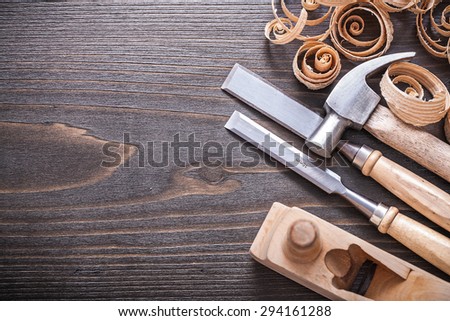 Planer claw hammer metal firmer chisels and wooden curled shavings on vintage wood board construction concept.