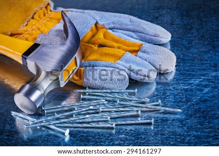 Protective glove variety of metal nails and claw hammer on scratched metallic surface construction concept.