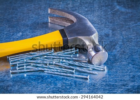 Close up image of metal construction nails with claw hammer on scratched metallic background maintenance concept.