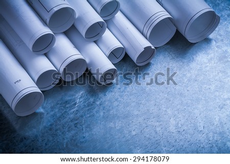 Rolls of white construction drawings on scratched metallic background building and architecture concept.