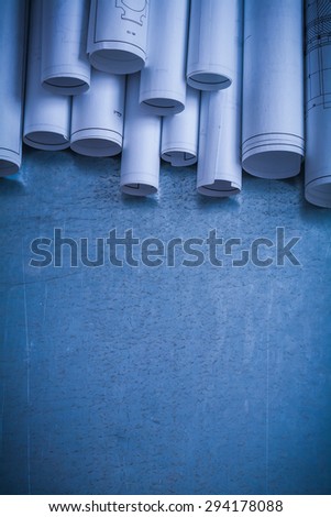 Rolled up white architectural blueprints on scratched metallic surface construction concept.