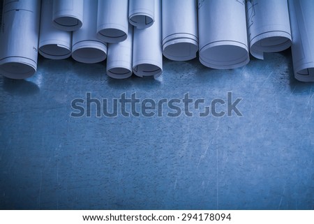 Rolled white blueprints on scratched metallic surface copy space image construction concept.