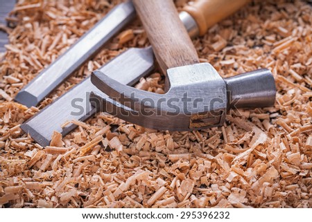 Claw hammer and chisels in wooden shavings on vintage wood board construction concept.