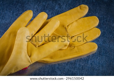 Pair of leather protective gloves on scratched metallic background construction concept.