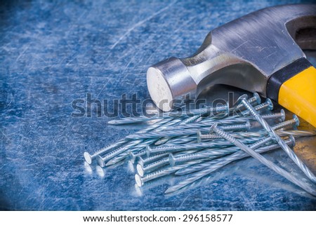 Steel construction nails with claw hammer on scratched metallic background horizontal view maintenance concept.