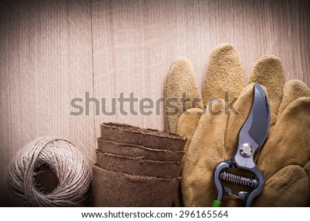 Sharp pruning shears leather safety gloves peat pots and hank of string on vintage wooden board gardening concept.