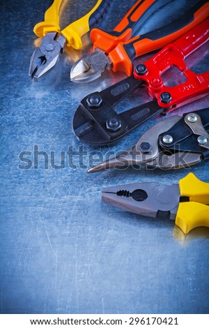 Composition of bolt cutter tin snips cutting pliers gripping tongs on scratched vintage metallic surface construction concept.