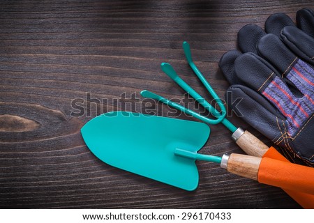 Gardening safety gloves hand spade and rake on vintage wooden board agriculture concept.