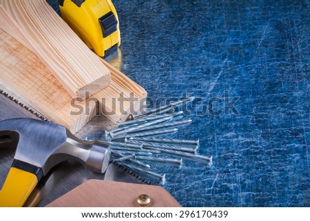 Composition of metal nails hammer wooden bricks hacksaw tape-measure on scratched metallic surface construction concept.