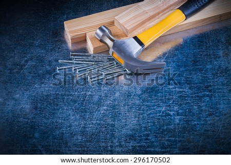 Construction nails claw hammer and wooden bricks on scratched metallic surface maintenance concept.