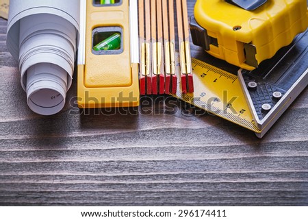 Wooden meter square ruler measuring tape rolled blueprints and construction level on vintage wood board maintenance concept.