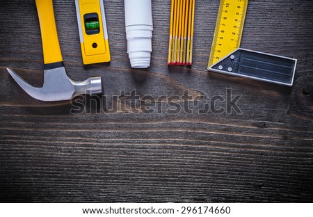 Yellow construction level square ruler rolled up blueprint wooden meter and hammer on vintage wood background maintenance concept.