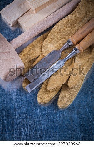 Wooden mallet bricks flat chisels and protective gloves on scratched metallic surface construction concept.