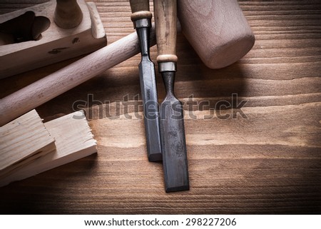 Wooden hammer stud planner flat chisels on wood board construction concept.