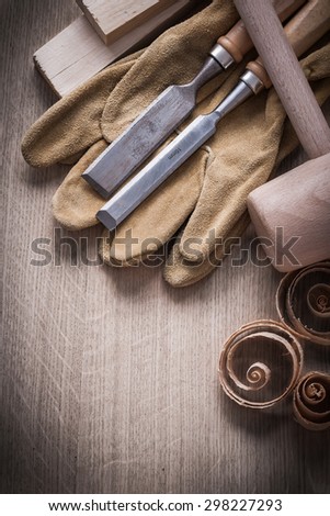 Wooden planks hammer curled up shavings flat chisels leather working gloves on wood board construction concept.