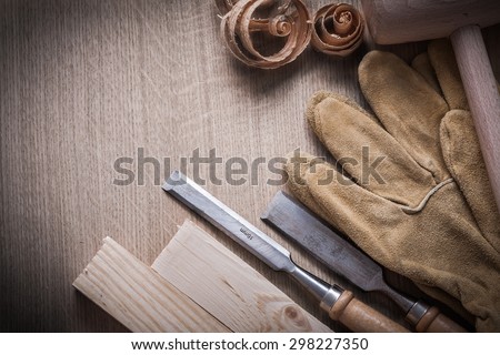 Wooden building boards mallet curled up shavings firmer chisels leather gloves on wood background construction concept.