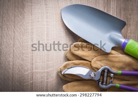 Pruning shears hand spade and leather safety gloves on wood board gardening concept.