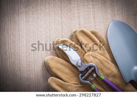 Sharp pruning shears hand spade and leather safety gloves on wood board agriculture concept.