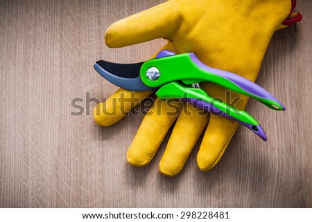 Leather gardening safety glove with sharp metal secateurs on wooden board agriculture concept.
