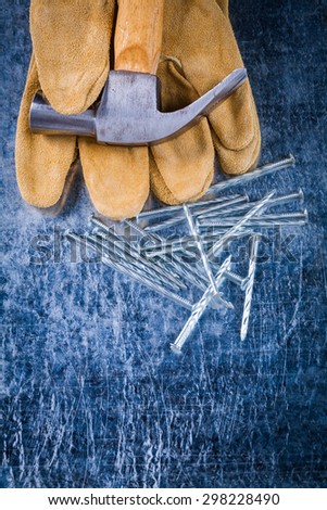 Leather construction gloves nails and claw hammer on scratched metallic surface building concept.