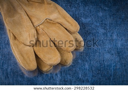 Leather brown construction gloves on scratched metallic surface building concept.