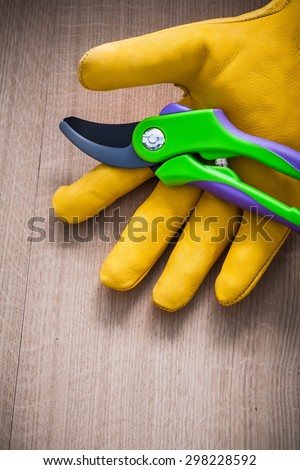 Leather gardening protective glove with garden pruner on wooden board agriculture concept.