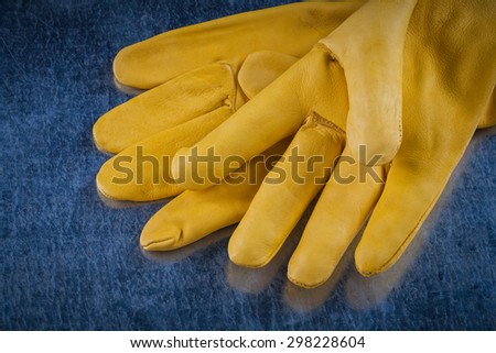Leather protective gloves on scratched metallic background close up view construction concept.