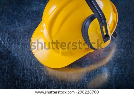 Noise reduction earmuffs and building helmet on scratched metallic surface construction concept.
