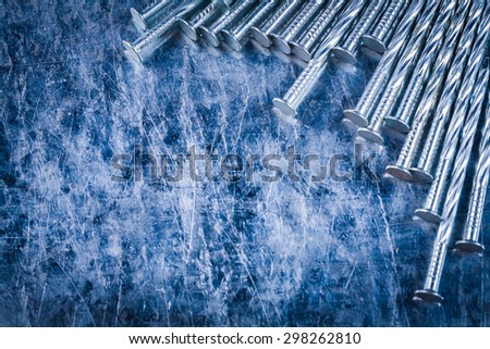 Collection of metal construction nails on scratched metallic background close up view building concept.