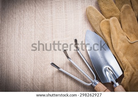 Copyspace of steel gardening trowel fork with hand spade and leather safety gloves on wooden board agriculture concept.